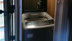 Eine Samsung Waschmaschine in einem kleinen Raum mit einer Holzwand und einem Fenster.