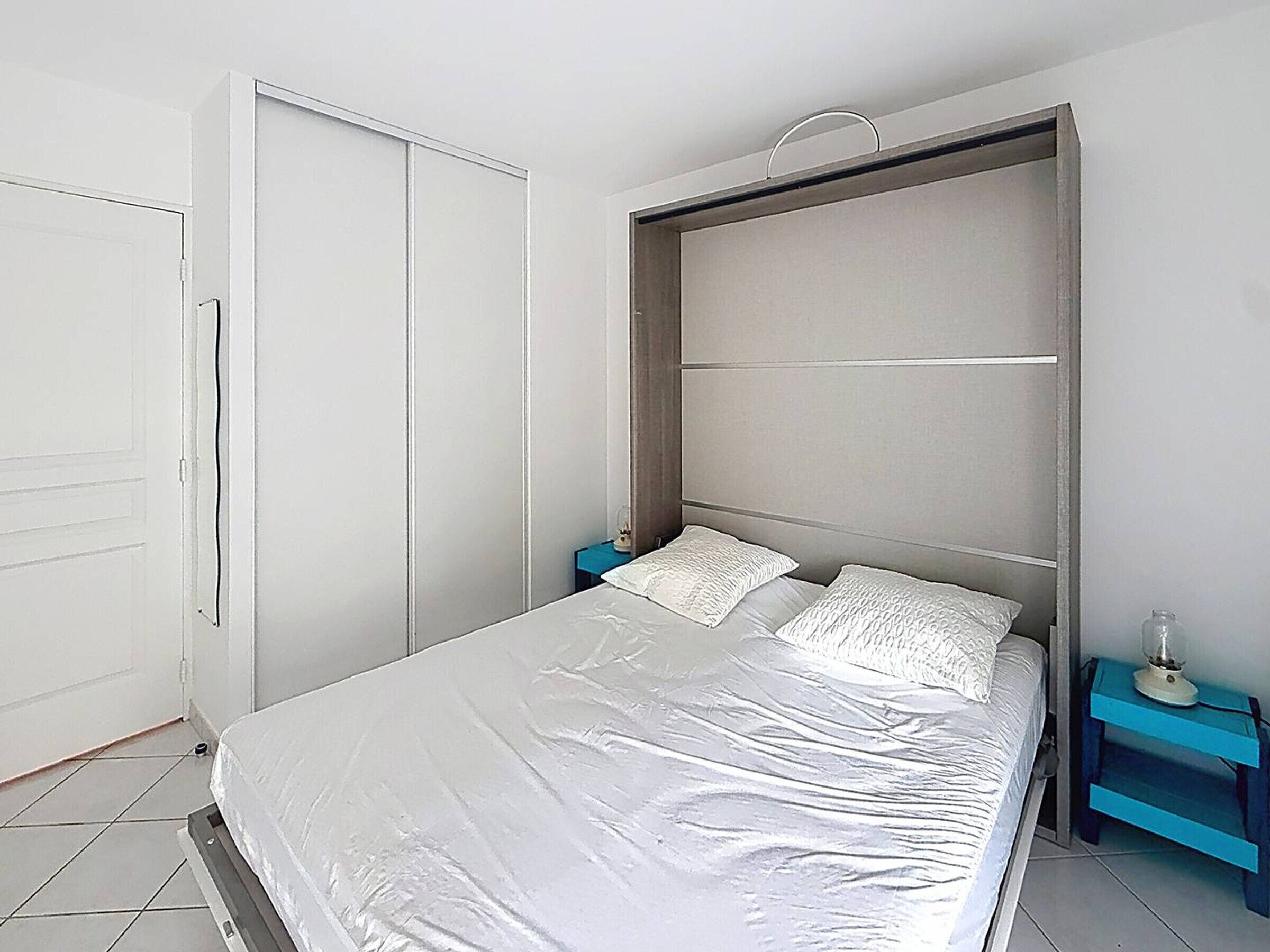 Un dormitorio con cama, armario y mesita de noche.