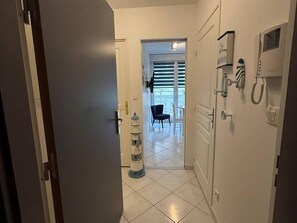Ein Flur mit einer Tür, einem Telefon und einem Stuhl im Hintergrund.