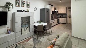Un salon moderne avec un canapé, une table à manger et une cuisine en arrière-plan.