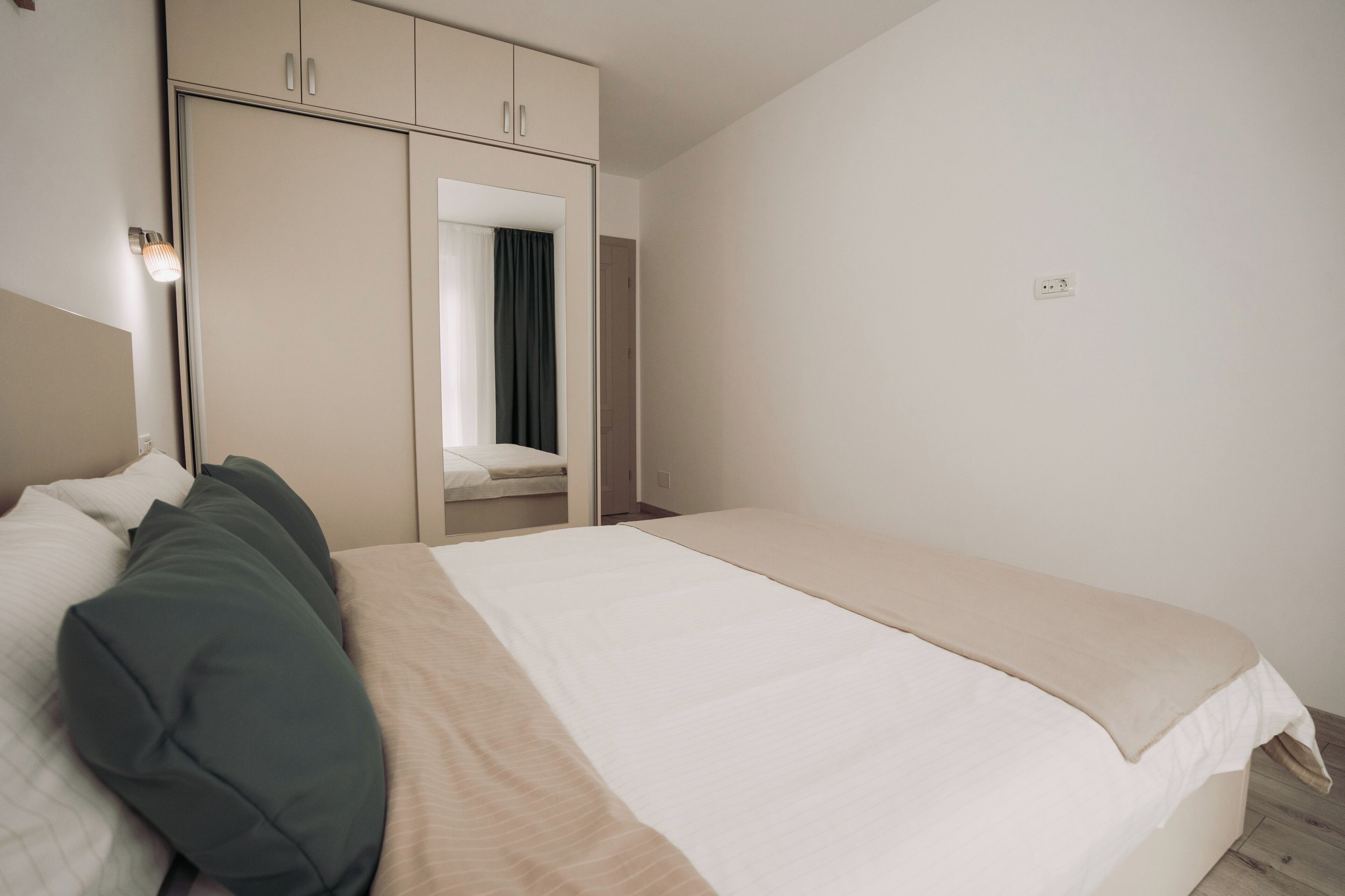 Een slaapkamer met een bed, een kledingkast, een spiegel en een lamp.