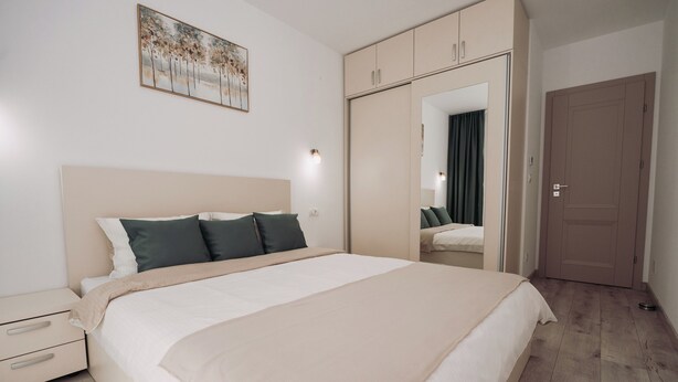 Un dormitorio con cama, mesita de noche, armario, espejo y un cuadro en la pared.