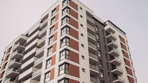 Un edificio residencial de varios pisos con balcones, ventanas amplias y un diseño arquitectónico moderno.