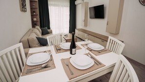 Un comedor con una mesa dispuesta para cuatro, una botella de vino y un televisor montado en la pared.