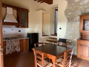 A kitchen with wooden cabinets, a dining table, and chairs. There is a stove, a refrigerator, and a tiled backsplash. - Villa Preselle Country Resort (Preselle)