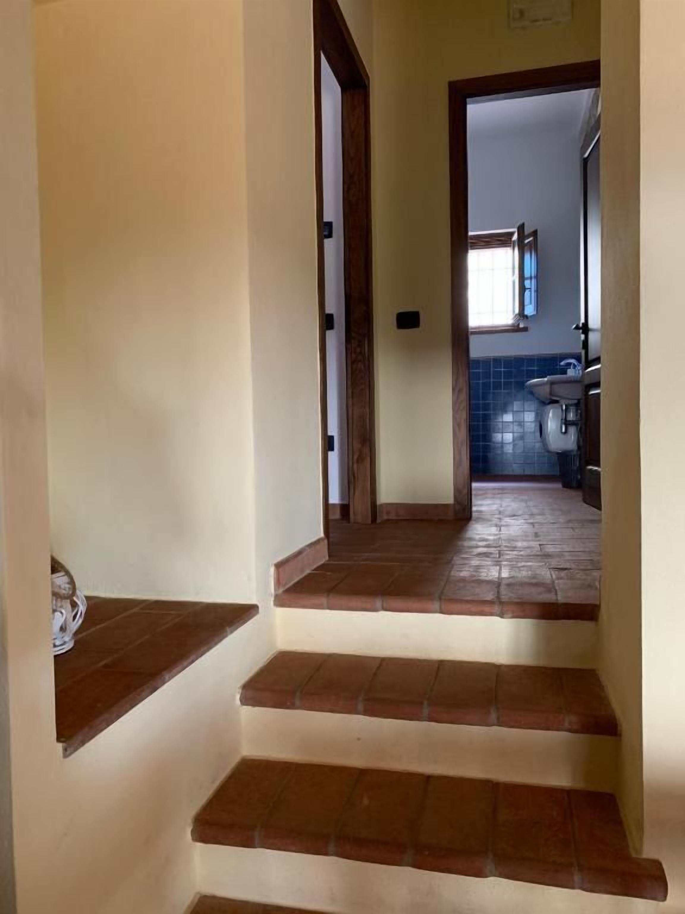A staircase leading to a bathroom with a window and a sink.