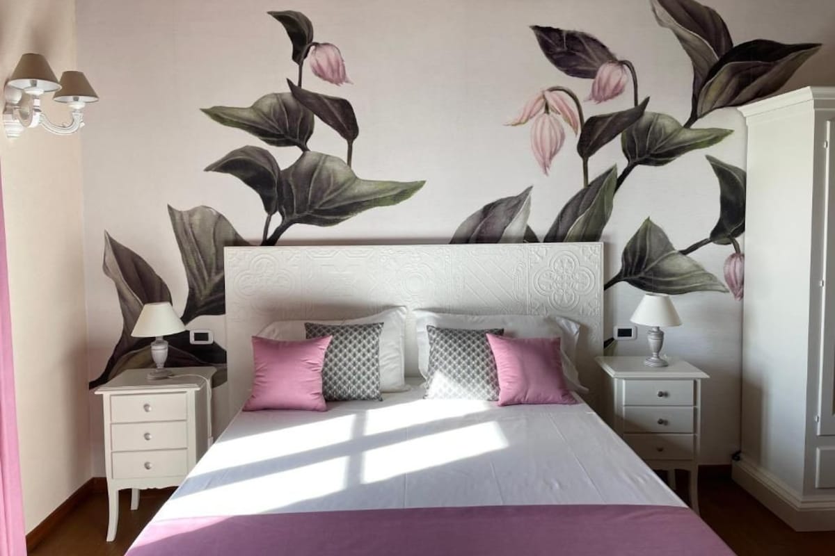 A bedroom with a bed, nightstands, a dresser, and a wall mural.