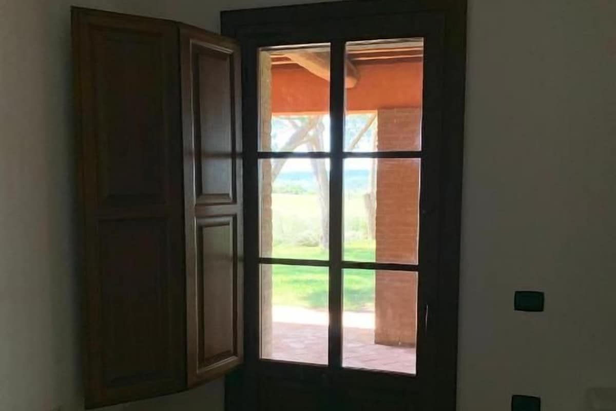 A room with a bed, a door leading to an outdoor area, and a wall-mounted cabinet.