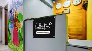 Ein Empfangsbereich mit Wandgemälde, einem Schild mit der Aufschrift 'Collection Company-Serviced' und drei Uhren an der Wand.