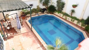 A swimming pool with a tiled deck, a covered seating area, and potted plants. - Dar Yala, the Algerian home of hospitality and tradition. A haven of peace (Zéralda)