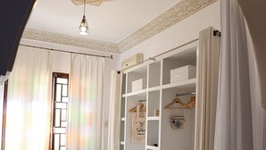 A room with a marble floor, a hanging light fixture, a wardrobe with shelves, and a door with a window. - Dar Yala, the Algerian home of hospitality and tradition. A haven of peace (Zéralda)