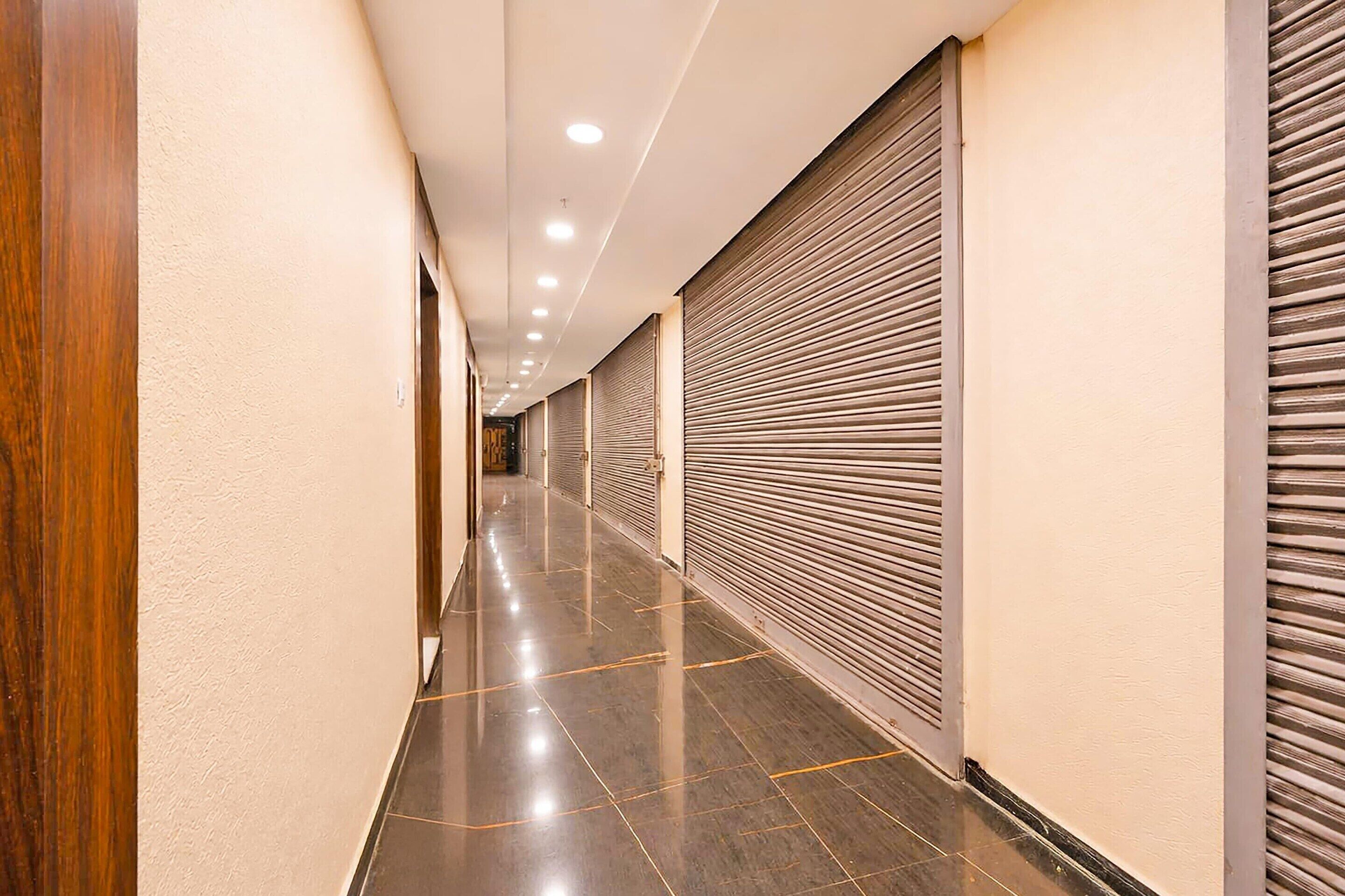 Un pasillo con tiendas cerradas y persianas bajadas, suelo pulido e iluminación empotrada.