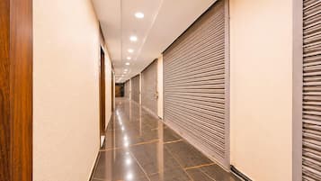 A corridor with closed shuttered storefronts, a polished floor, and recessed lighting.