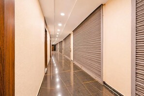 Un couloir bordé de devantures de magasins fermées et voletées, doté d’un sol poli et d’un éclairage encastré.