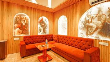 Ein Zimmer mit einem roten, gepolsterten Sofa, Holzboden und drei an der Wand befestigten Kunstwerken.