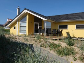A yellow building with a covered patio, large windows, and a chimney. - Restorative Danish Home (Grossenbrode)
