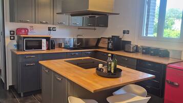 A modern kitchen with a central island, stainless steel appliances, and a red refrigerator.