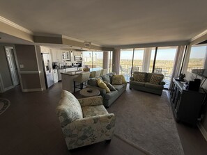 A spacious living area with a sofa, a coffee table, and a kitchen in the background. - LOCATION, Location! Oceanfront 2 bed condo in desired Shore drive paradise bliss (Myrtle Beach)