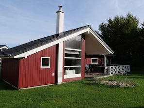 A red building with a chimney, large windows, and a covered outdoor seating area. - 4 Star Holiday Home in Grossenbrode (Grossenbrode)