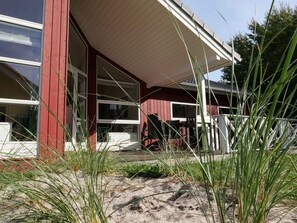 A red building with a covered porch, large windows, and outdoor seating. - 4 Star Holiday Home in Grossenbrode (Grossenbrode)