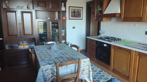 Una cocina con armarios de madera, una mesa de comedor con sillas y una estufa.