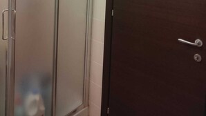 Un baño con cabina de ducha de vidrio y una puerta de madera oscura.