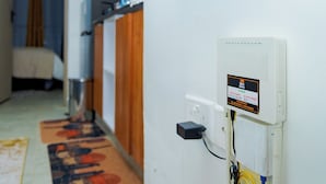 Um corredor com um armário de madeira, uma caixa elétrica branca fixada na parede e um tapete de entrada.