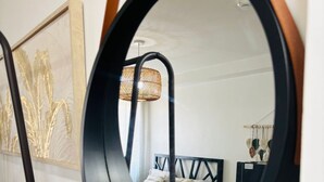 A round mirror reflecting a bed, a bedside table, and a wall-mounted picture frame. - Urban Oasis Symphony Pool (Cebu City)