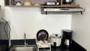 A compact kitchen with a sink, stove, and a coffee maker. - Urban Oasis Symphony Pool (Cebu City)