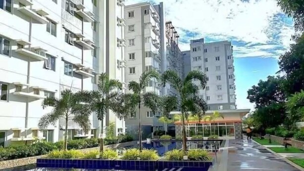 A modern building with a swimming pool, surrounded by greenery and a clear sky. - Urban Oasis Symphony Pool (Cebu City)