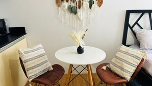 A small room with a round table, two chairs, a bed, and a wall decoration. - Urban Oasis Symphony Pool (Cebu City)