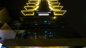 A building with a prominent illuminated sign reading 'TOWNHOUSE OAK' and a 'Company-Serviced' label.