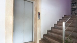 A staircase with a metal handrail leading to a closed door with a control panel.
