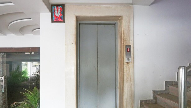 An elevator with a digital display, a staircase with metal railings, and a door with a small framed picture above it.