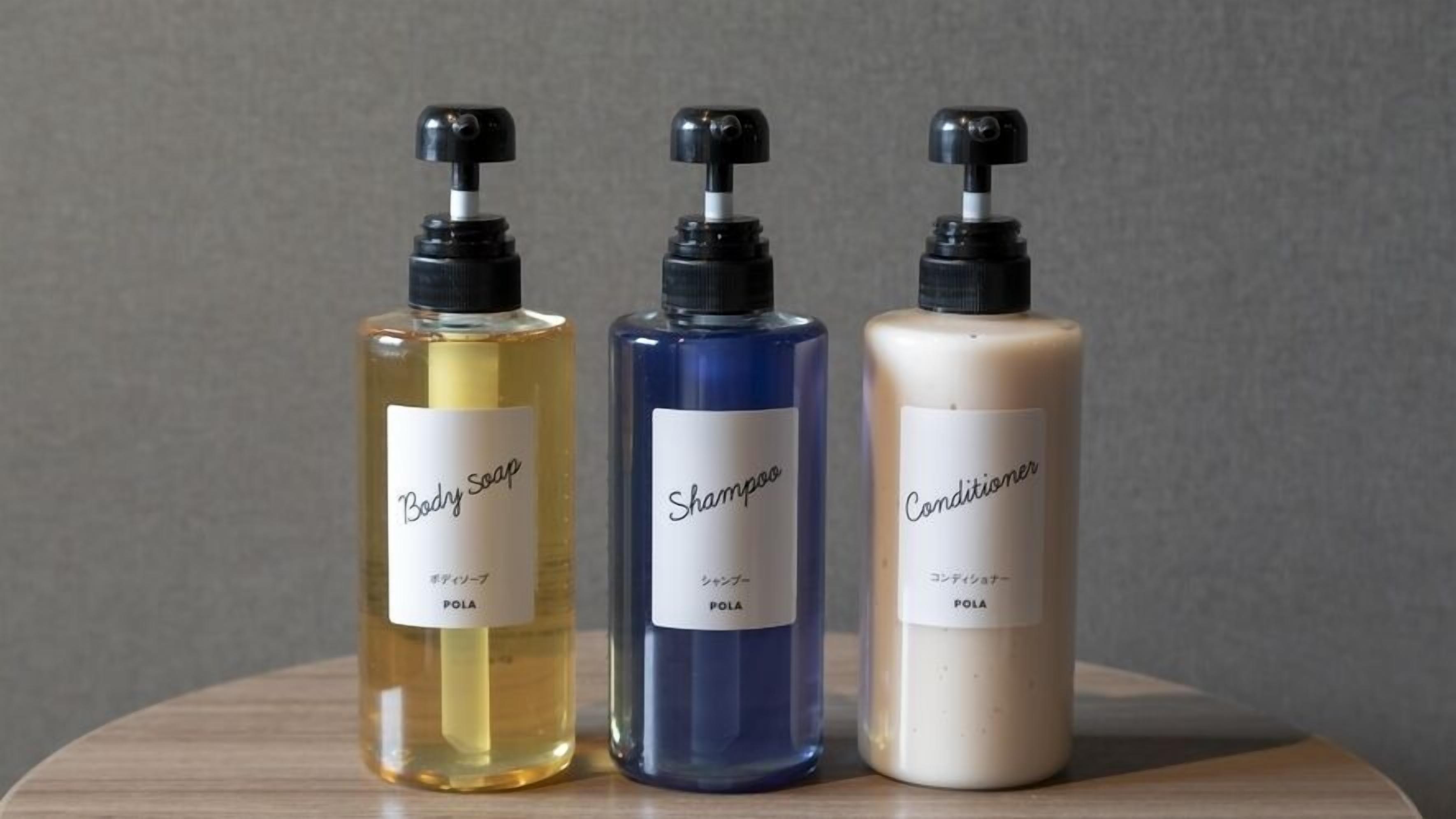 Tres botellas de productos para el cuidado corporal sobre una superficie de madera.
