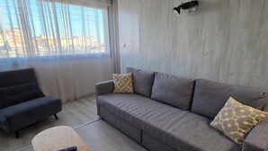 Ein modernes Wohnzimmer mit einem grauen Sofa, einem Holztisch und einem schwarzen Sessel.