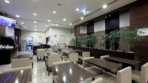 Un restaurante con varias mesas y sillas, una barra y una pantalla de televisión.