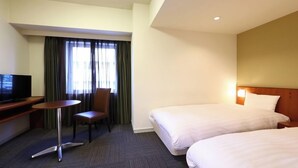 Habitación de hotel con dos camas, un escritorio, una silla, un televisor y una ventana con cortinas.