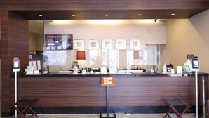 Un mostrador de recepción con pantalla digital, marcos con fotografías y una barra con servicios.
