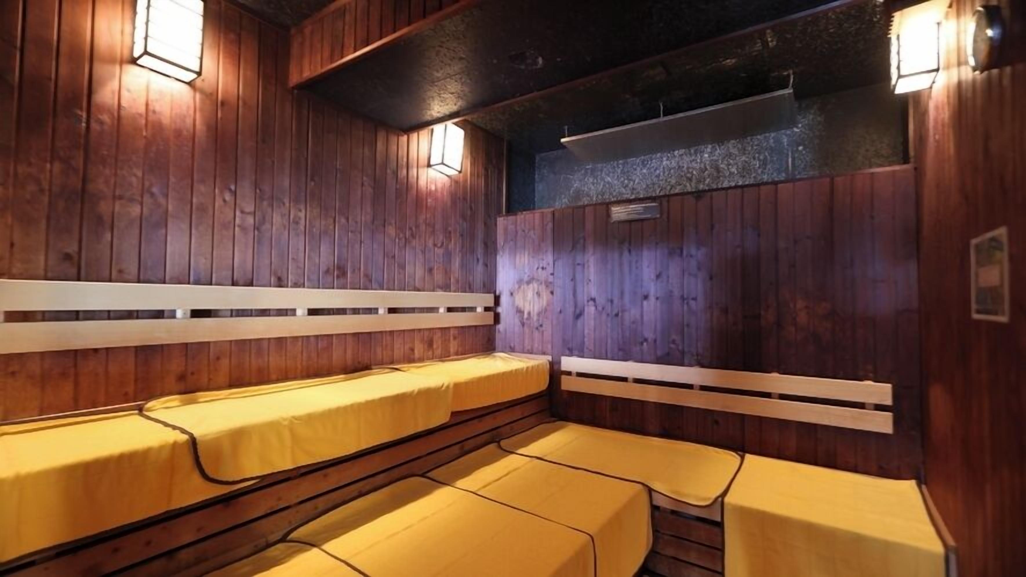 Un sauna avec des murs, des bancs et des lampes fixés au mur, le tout en bois.