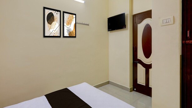 Une chambre d’hôtel avec un lit, un téléviseur à écran plat fixé au mur et deux œuvres d’art encadrées au-dessus du lit.