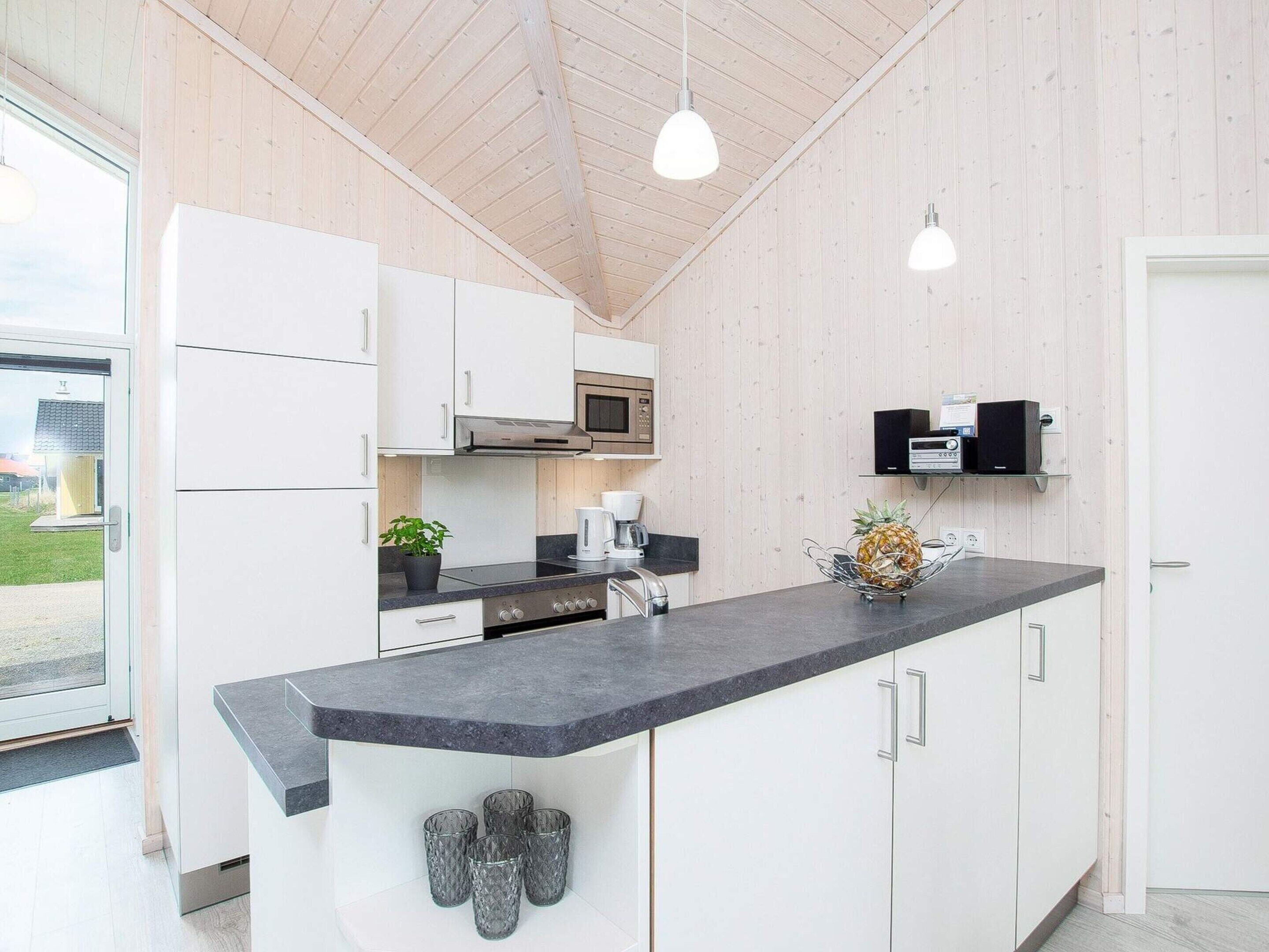 A modern kitchen with white cabinets, a granite countertop, a microwave, and a coffee maker.