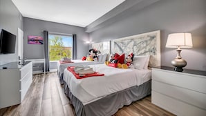 Une chambre d’hôtel avec un lit, un bureau, une télévision, une lampe et une fenêtre avec des rideaux.