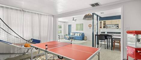 A room with a ping pong table, a hammock, and a colorful rug.