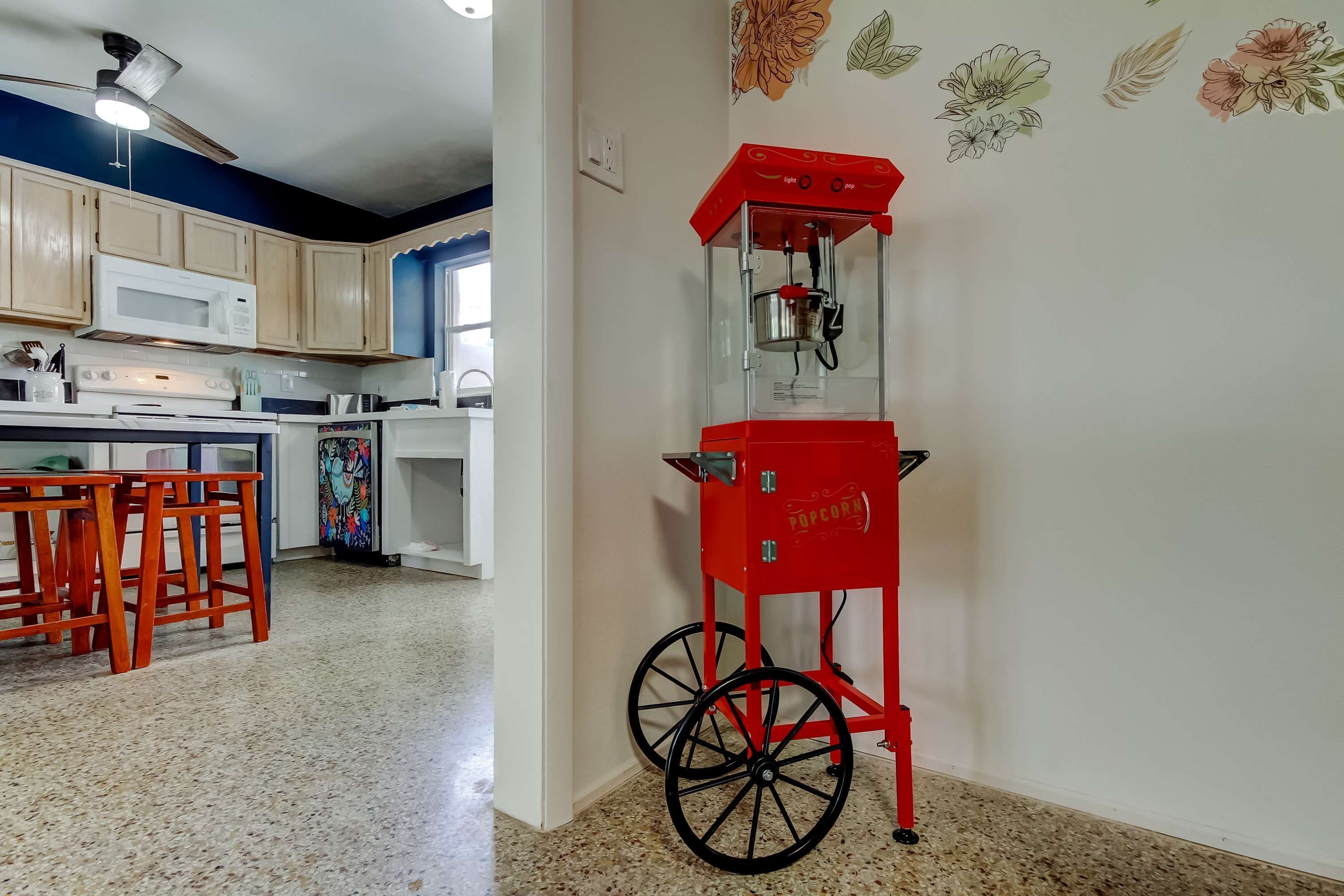 Una cocina con armarios de madera, un microondas, una estufa y una m áquina para palomitas roja.