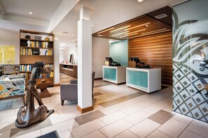A modern reception area with a wooden reception desk, a seating area, and a bookshelf.