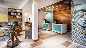 A modern reception area with a wooden reception desk, a seating area, and a bookshelf. - Staypineapple, Hotel Z, Gaslamp San Diego (San Diego)