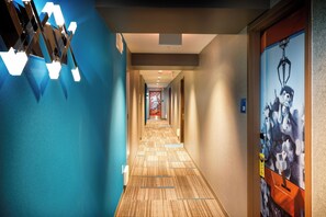 A hotel hallway with a blue wall, a patterned carpet, and a door with a poster. - Staypineapple, Hotel Z, Gaslamp San Diego (San Diego)