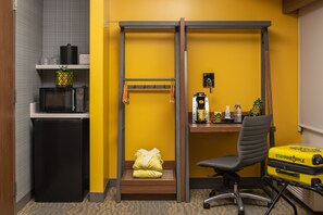 A compact hotel room with a kitchenette, a bed with a yellow pillow, a desk with a coffee machine, and a suitcase on the floor. - Staypineapple, Hotel Z, Gaslamp San Diego (San Diego)