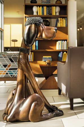 Une sculpture de chien dans un salon moderne, avec une bibliothèque et un canapé.